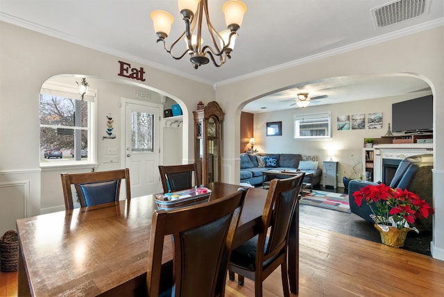 dining room with ornamental molding, ceiling fan with notable chandelier, and wood-type flooring