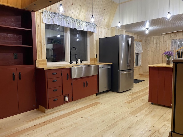 kitchen with hanging light fixtures, butcher block countertops, wooden walls, and stainless steel appliances