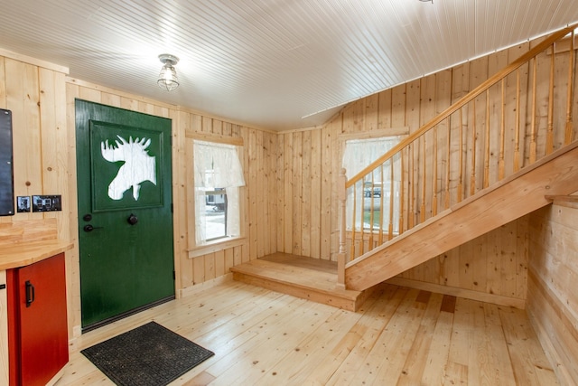 entrance foyer with light wood-type flooring and wood walls