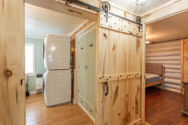 hallway featuring wood-type flooring, rustic walls, and a barn door