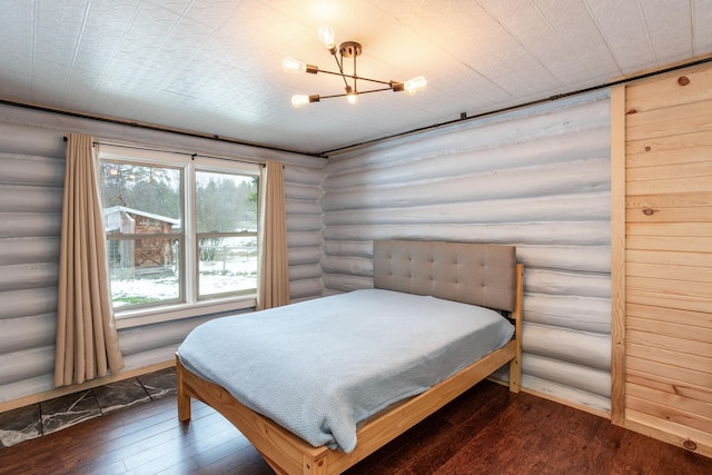 bedroom with dark hardwood / wood-style floors, log walls, and an inviting chandelier