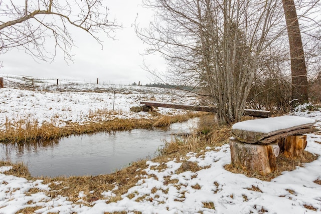 yard covered in snow featuring a water view