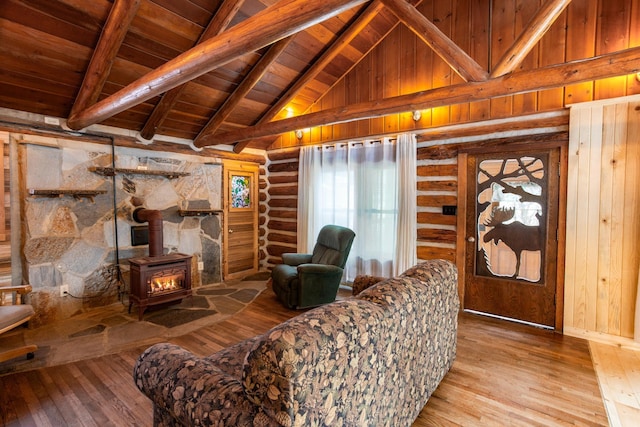 living room featuring log walls, wood-type flooring, beamed ceiling, a wood stove, and wooden ceiling