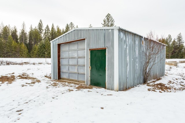 snow covered structure featuring a garage