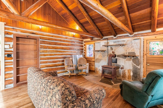 living room with a wood stove, rustic walls, high vaulted ceiling, wooden ceiling, and beam ceiling