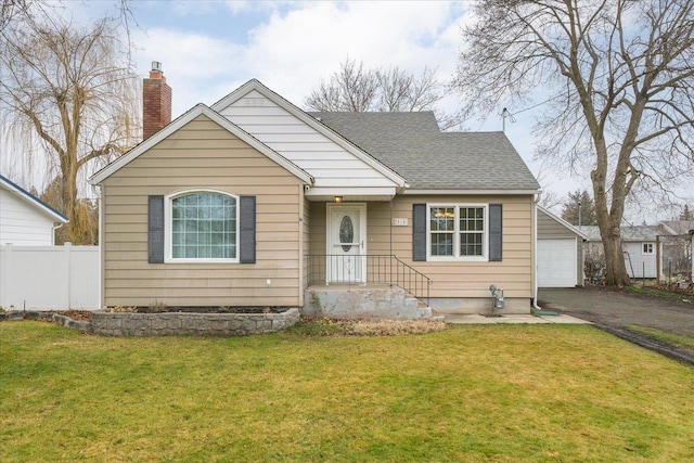 bungalow-style home featuring a front lawn, an outdoor structure, and a garage