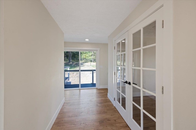 corridor featuring french doors, a textured ceiling, and hardwood / wood-style flooring