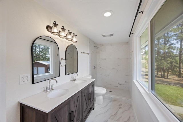 bathroom featuring toilet, vanity, and tiled shower