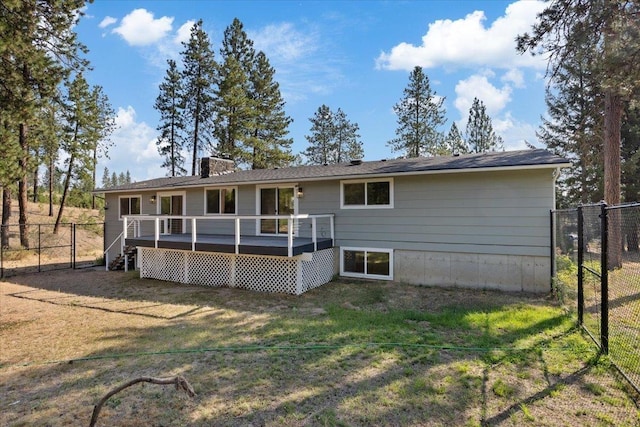 rear view of house featuring a lawn and a deck