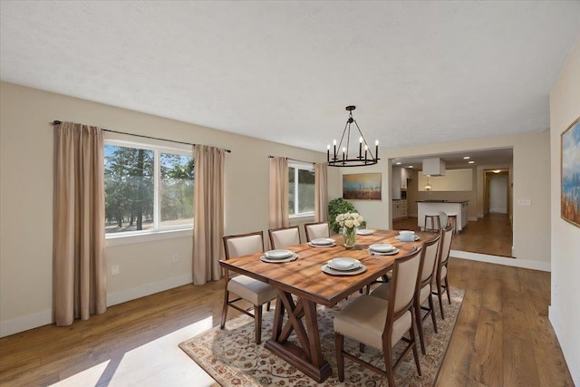 dining space featuring wood-type flooring and a notable chandelier