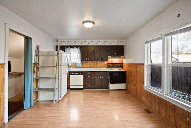 kitchen with white appliances, light hardwood / wood-style flooring, dark brown cabinets, and wooden walls