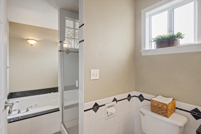 bathroom featuring toilet, shower with separate bathtub, and tile walls