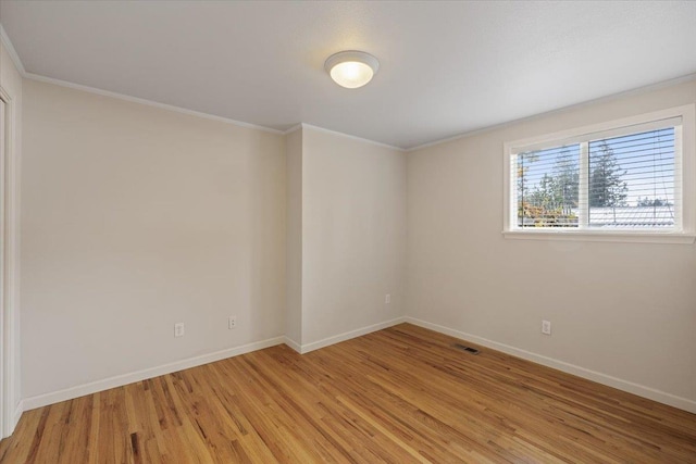 empty room with crown molding and light hardwood / wood-style flooring