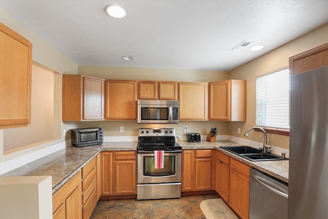 kitchen with appliances with stainless steel finishes, light stone counters, and sink