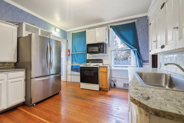 kitchen with hardwood / wood-style floors, electric range, sink, stainless steel refrigerator, and white cabinets