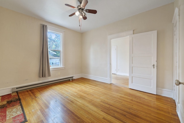 empty room featuring ceiling fan, baseboard heating, and wood-type flooring