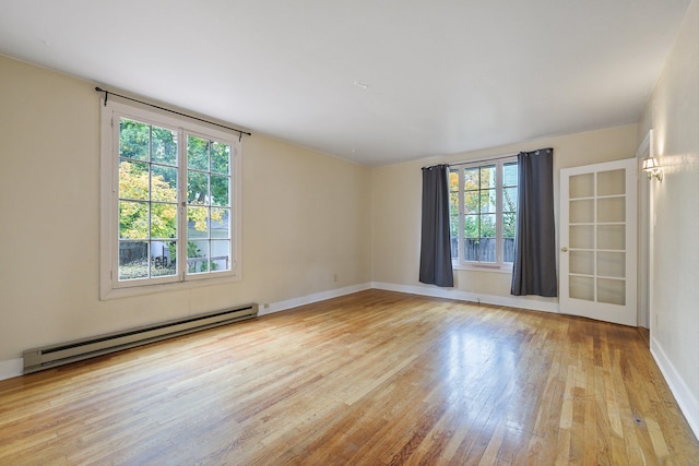 unfurnished room featuring baseboard heating and light hardwood / wood-style floors