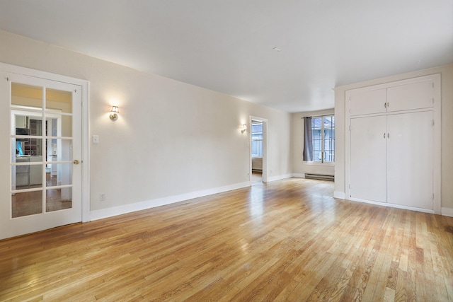 empty room with baseboard heating and light hardwood / wood-style flooring