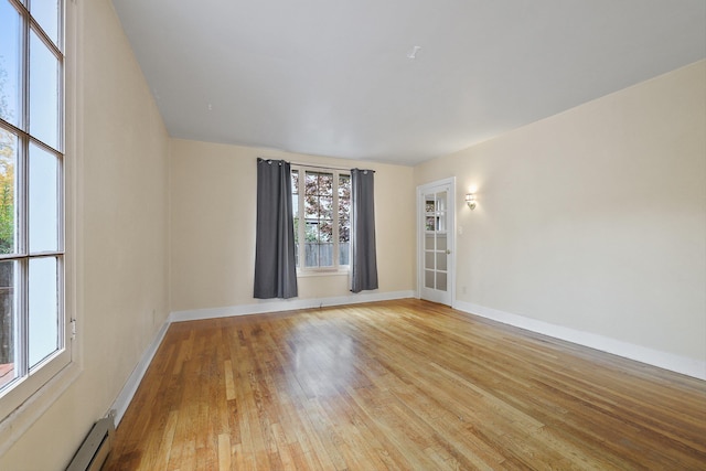 spare room with light wood-type flooring, baseboard heating, and a wealth of natural light