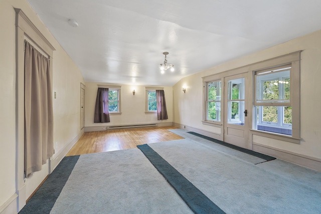 empty room featuring a baseboard radiator, lofted ceiling, a chandelier, and light wood-type flooring