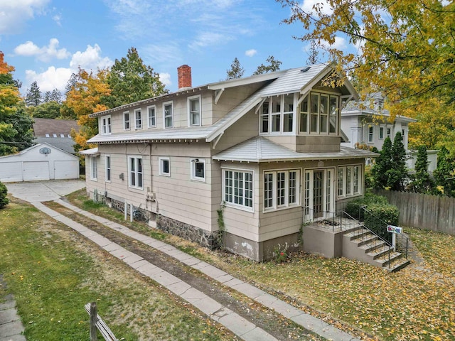 rear view of property featuring a garage, a sunroom, and an outdoor structure