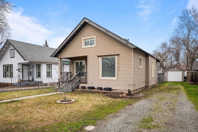 bungalow-style home with a garage, a front yard, and an outdoor structure