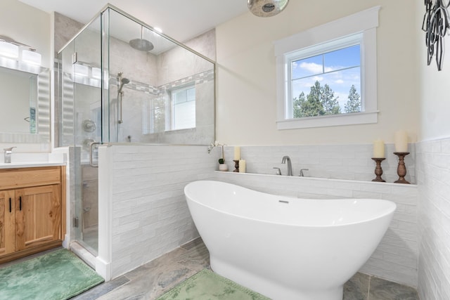 bathroom with plus walk in shower, tile walls, and vanity