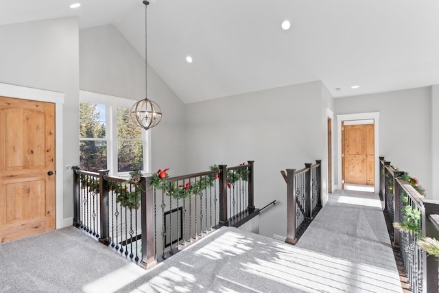 hallway with light carpet, high vaulted ceiling, and a notable chandelier