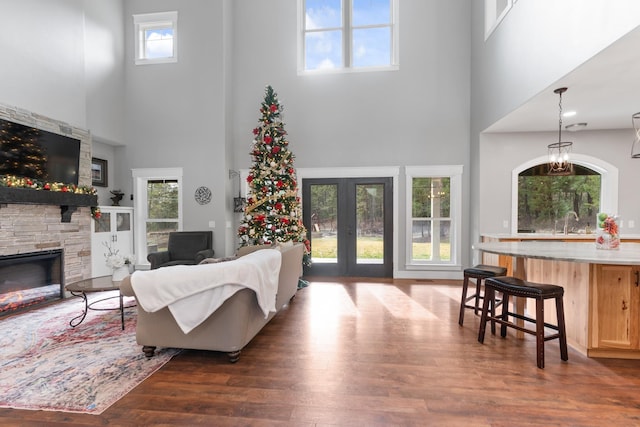 living room featuring a towering ceiling, dark hardwood / wood-style flooring, french doors, a fireplace, and sink