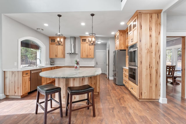 kitchen with a healthy amount of sunlight, stainless steel appliances, wall chimney exhaust hood, and a center island