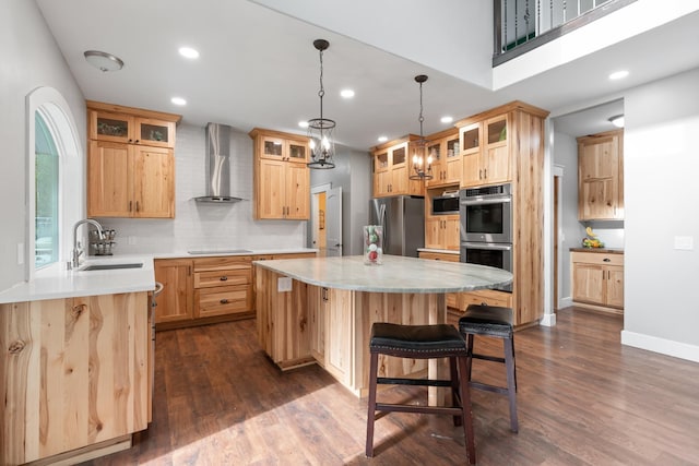 kitchen featuring appliances with stainless steel finishes, dark hardwood / wood-style floors, wall chimney range hood, a kitchen island, and sink