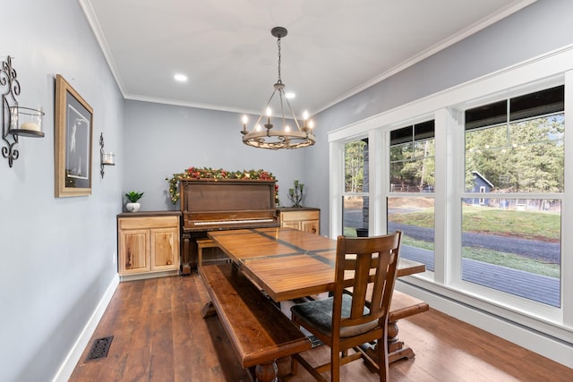 dining room featuring crown molding, dark hardwood / wood-style flooring, and an inviting chandelier