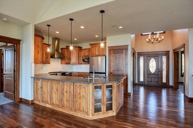 kitchen with decorative light fixtures, a notable chandelier, wall chimney exhaust hood, and stainless steel appliances