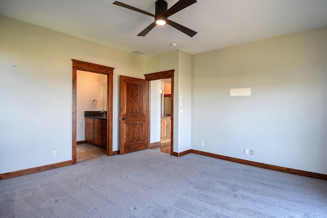 unfurnished bedroom featuring light carpet, ceiling fan, and ensuite bathroom