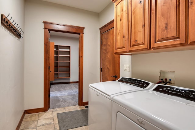 clothes washing area with separate washer and dryer and cabinets