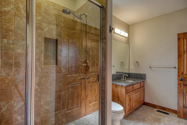 bathroom featuring toilet, vanity, and a shower with door