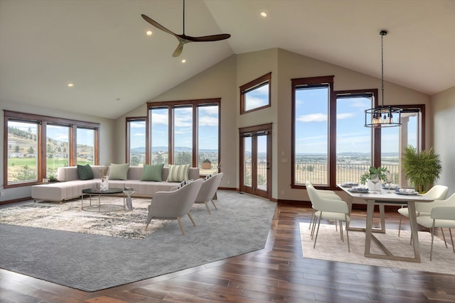 living room featuring ceiling fan with notable chandelier, plenty of natural light, and high vaulted ceiling