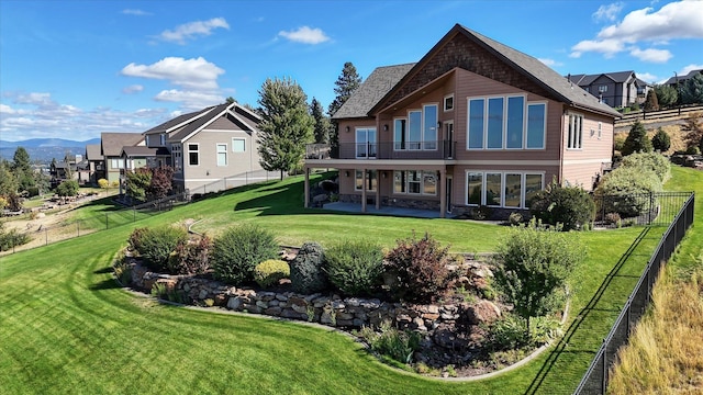 rear view of house with a lawn, a patio area, and a balcony