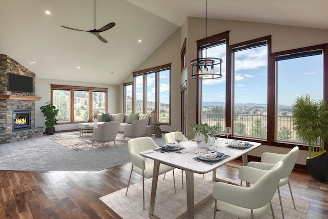 dining area with ceiling fan, high vaulted ceiling, and a fireplace