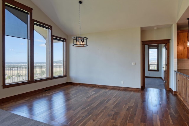 unfurnished dining area featuring dark wood-type flooring, a wealth of natural light, and a notable chandelier