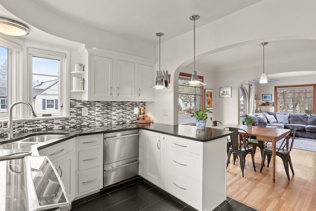 kitchen with tasteful backsplash, pendant lighting, kitchen peninsula, sink, and white cabinetry