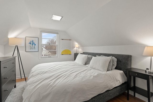 bedroom with lofted ceiling and light wood-type flooring