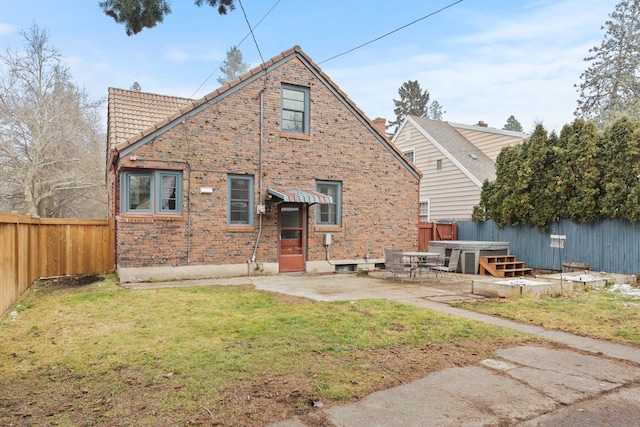 back of house with a hot tub, a lawn, and a patio