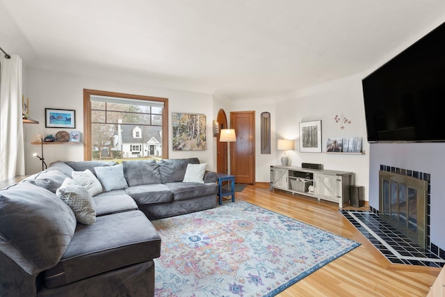 living room featuring a tile fireplace and hardwood / wood-style flooring