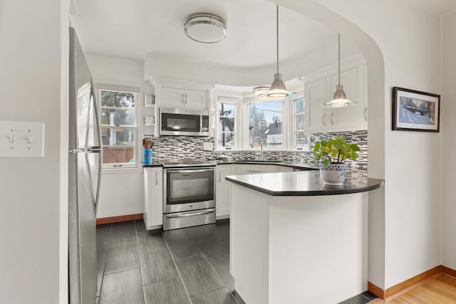 kitchen featuring appliances with stainless steel finishes, tasteful backsplash, pendant lighting, white cabinets, and sink