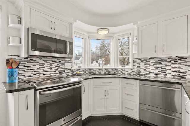 kitchen with appliances with stainless steel finishes, dark tile patterned flooring, white cabinets, and sink