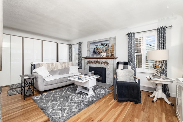 living room with light wood-type flooring and a tiled fireplace