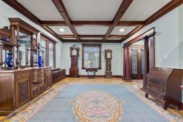 interior space featuring baseboards, ornate columns, beamed ceiling, and coffered ceiling
