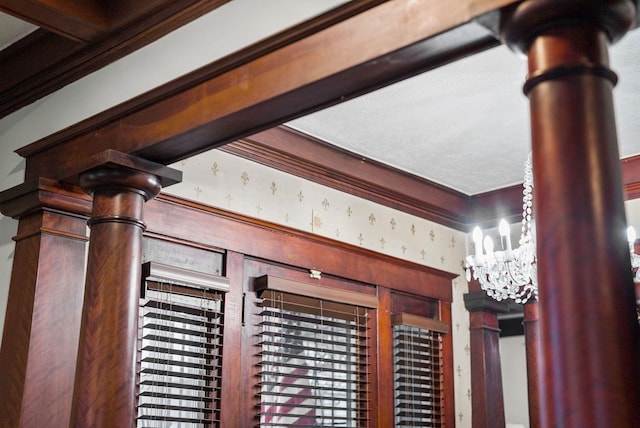 details with wallpapered walls, decorative columns, and a notable chandelier