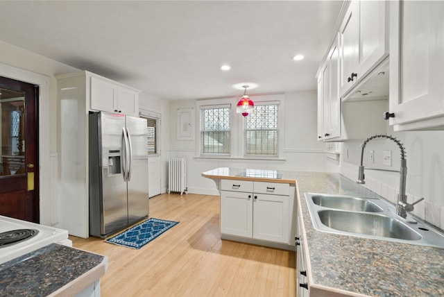 kitchen with stainless steel fridge with ice dispenser, a sink, light wood-type flooring, white cabinetry, and radiator heating unit
